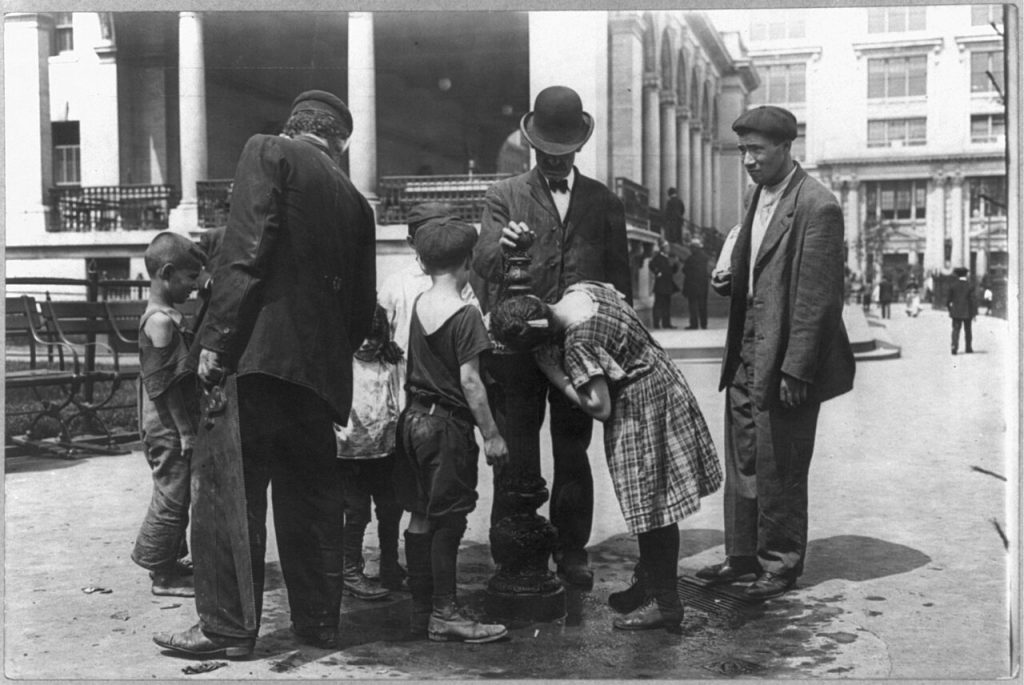Personas tomando agua durante un dia caluroso en la ciudad