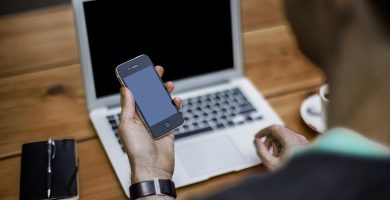 Persona usando un smartphone junto a una laptop